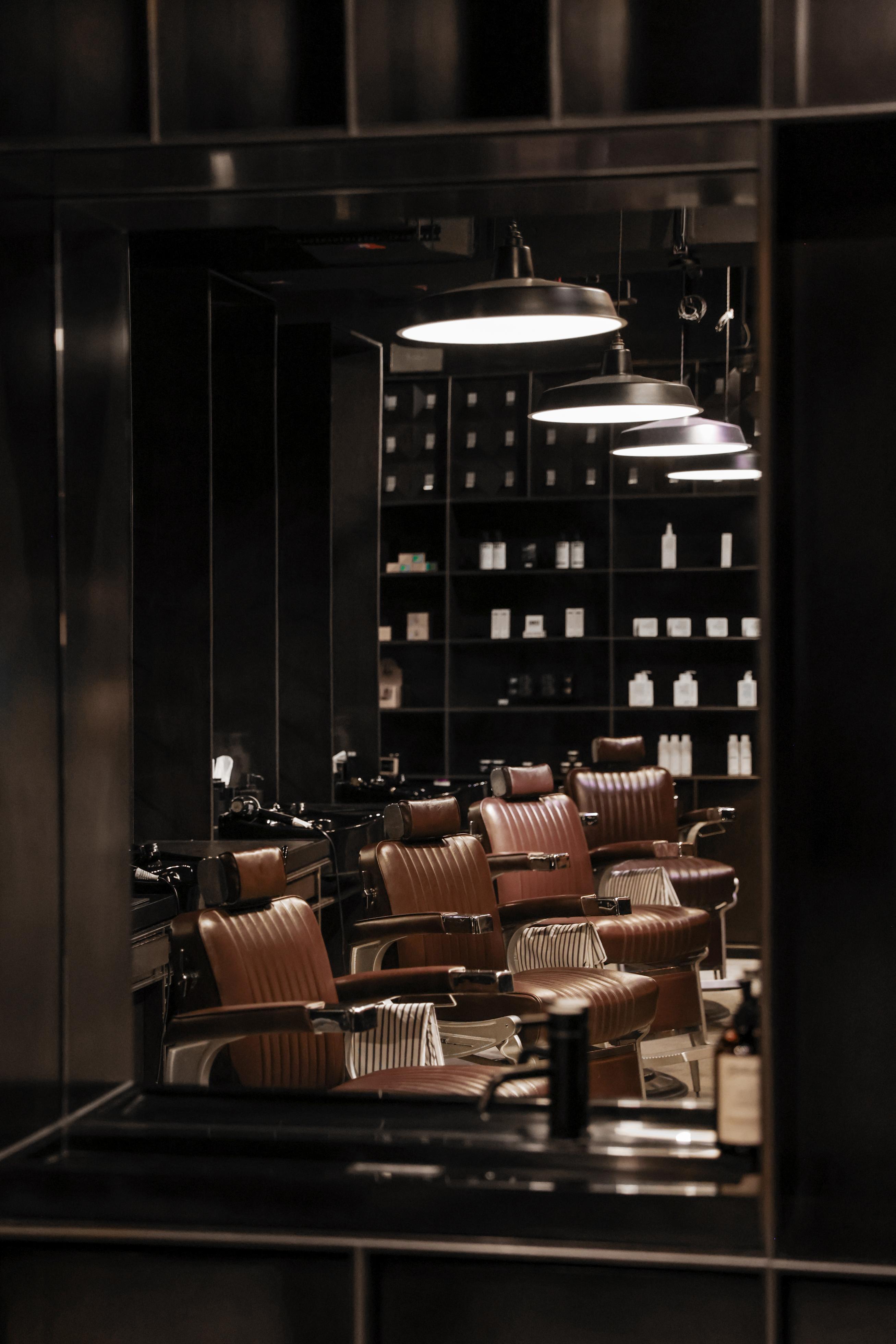 Barbershop interior with mirrors reflecting chairs and shelves.